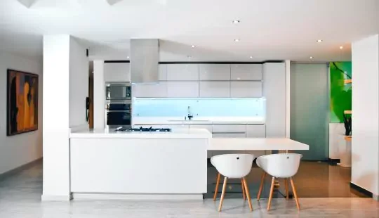 Cuisine ouverte blanche avec îlot et chaises en bois clair