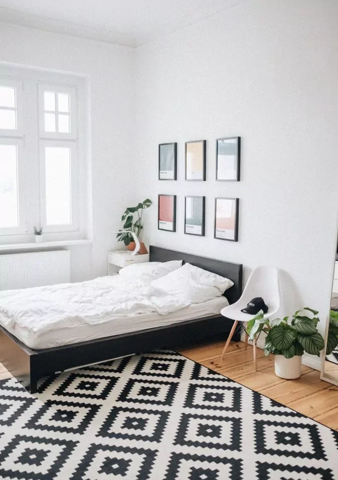 Chambre lumineuse, linge de lit blanc, tapis graphique et mobilier en bois